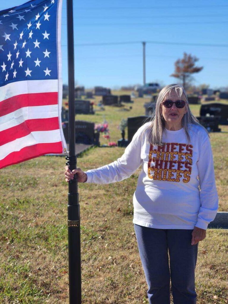 Linda Lewis holding flag pole flying the American Flag.